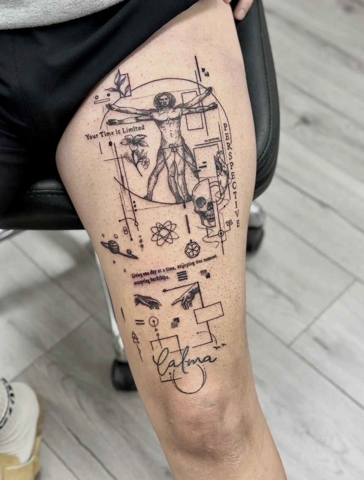 קעקוע האדם הוויטרובי עם גיאומטריה ואלמנטים קטנים על הירך
